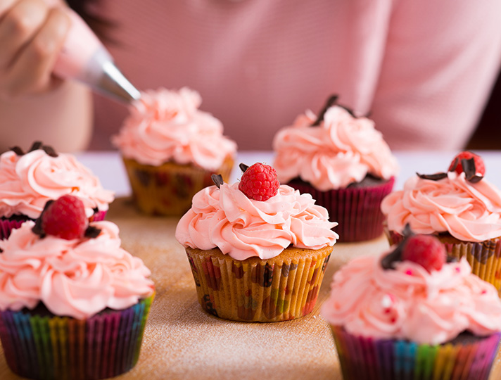 Cup cakes with pink icing topped with a cherry